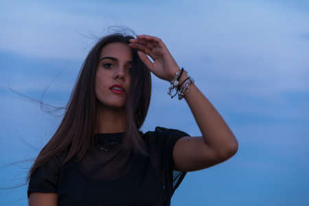beautiful young brunette girl posing a road in the middle of the field at sunsetの写真素材