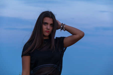beautiful young brunette girl posing a road in the middle of the field at sunsetの写真素材