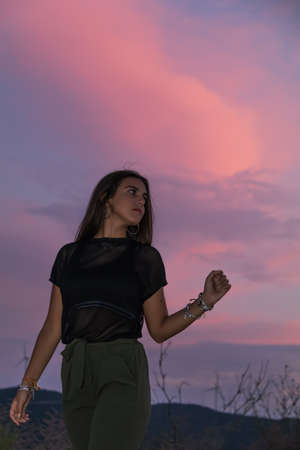 beautiful young brunette girl posing a road in the middle of the field at sunsetの写真素材
