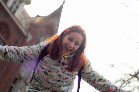 Redhead young woman in the street, dressed very warm, in winter, Bruges in Belgium. She is smiling to camera.の写真素材