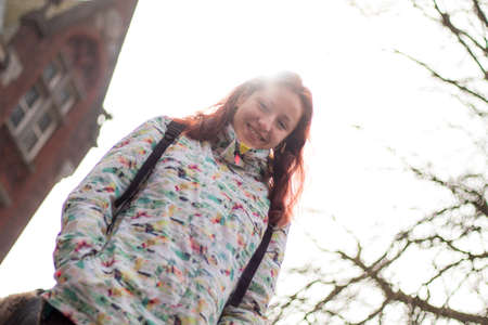 Redhead young woman in the street, dressed very warm, in winter, Bruges in Belgium. She is smiling to camera.の写真素材