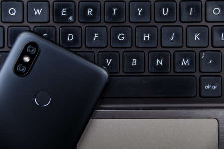Modern notebook and smartphone copy space. Mobile with dual camera and fingerprint readerの写真素材