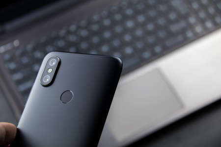 Modern notebook and smartphone copy space. Mobile with dual camera and fingerprint readerの写真素材