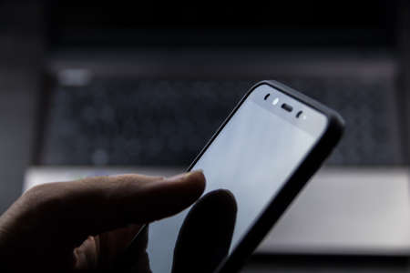hand using a modern mobile and a laptop backgroundの写真素材