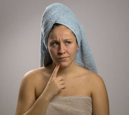 Dubious and angry young woman after shower with two towelsの写真素材