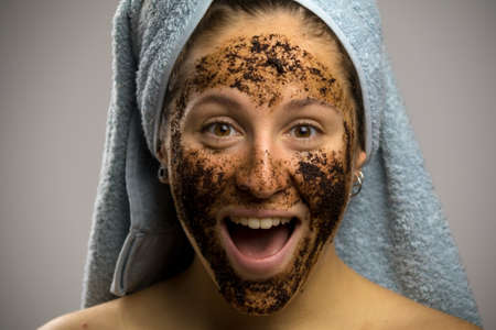 Shy girl screaming after taking a shower, face with homemade coffee creamの写真素材