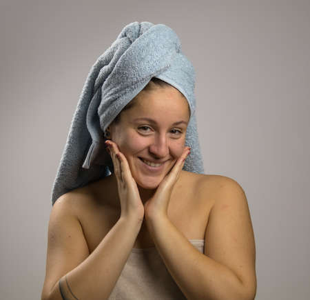 Young woman after shower with a towel and happy. Touching his faceの写真素材