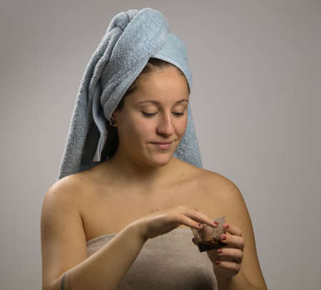Young woman after shower with a towel and smiling. Homemade remedy with coffee for spillの写真素材