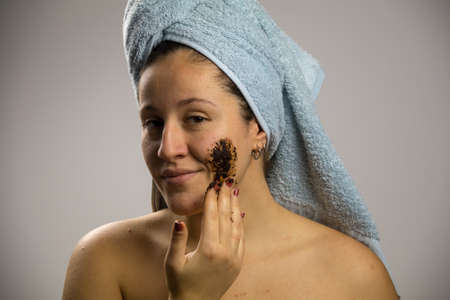 Young woman after shower with a towel and smiling, face with homemade coffee creamの写真素材