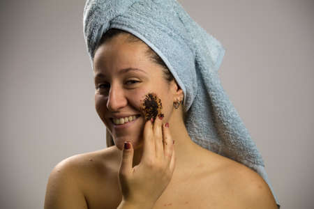 Young woman after shower with a towel and smiling. Homemade remedy with coffee for spillの写真素材