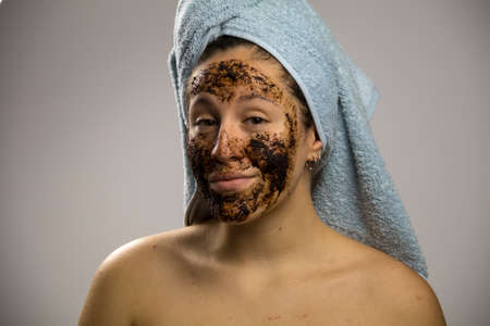 Young woman after shower with a towel and smiling, face with homemade coffee creamの写真素材