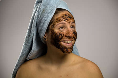 Young woman after shower with a towel and smiling, face with homemade coffee creamの写真素材