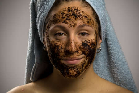 Young woman after shower with a towel and smiling, face with homemade coffee creamの写真素材