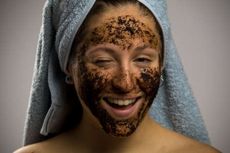 Young woman after shower with a towel and wink, face with homemade coffee creamの写真素材