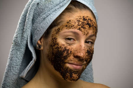 Young woman after shower with a towel and smiling, face with homemade coffee creamの写真素材