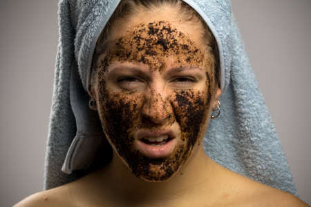 Angry girl after shower with two towels, face with homemade coffee creamの写真素材