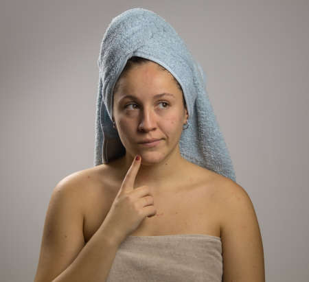 Dubious young girl after shower with two towels on white backgroundの写真素材