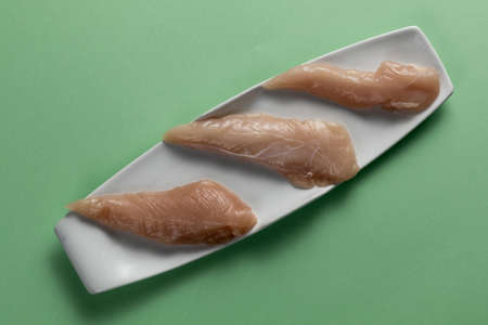 Raw chicken breasts on a green background. Elegant white plate. Top viewの写真素材
