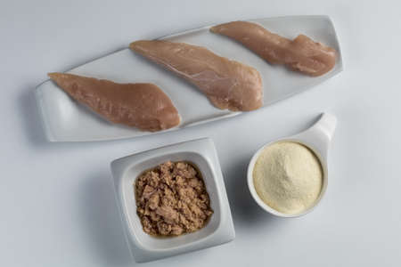 Raw chicken Breasts, tuna in oil and a whey protein scoop vanilla flavor. Sport nutrition. White tableの写真素材