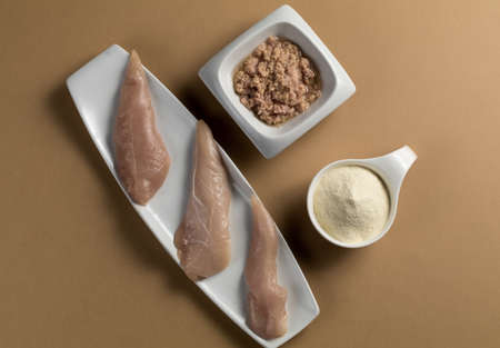 Sports bodybuilding supplement. White porcelain scoop with whey protein vanilla flavor powder, raw chicken breasts and tuna in oilの写真素材