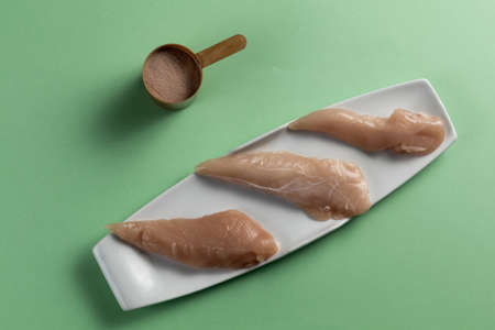 Raw chicken breasts and a whey protein scoop chocolate flavor. Sport nutrition. Top viewの写真素材