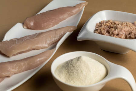 Sports bodybuilding supplement. White porcelain scoop with whey protein vanilla flavor powder, raw chicken breasts and tuna in oilの写真素材
