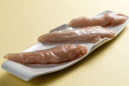 Raw chicken Breasts on a yellow table. Elegant white plateの写真素材