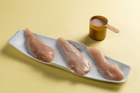 Raw chicken Breasts and a whey protein scoop chocolate flavor. Sport nutritionの写真素材