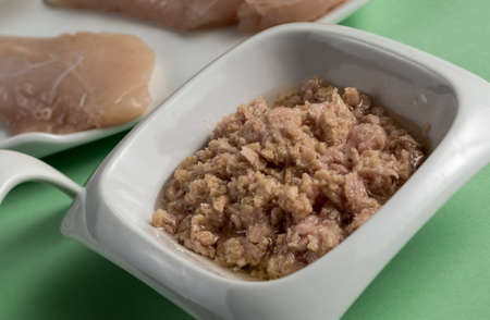 Tuna in oil and raw chicken breast on green tableの写真素材