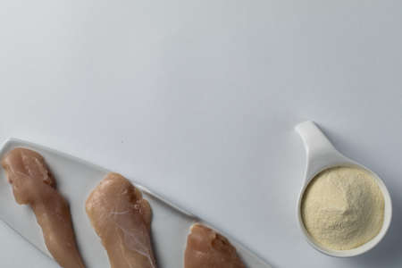 Raw chicken breasts and a scoop whey protein powder on a white table.Top view. Space Text. Sport nutritionの写真素材