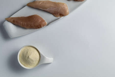 Raw chicken breasts and a scoop whey protein powder on a white table.Top view. Space Text. Sport nutritionの写真素材