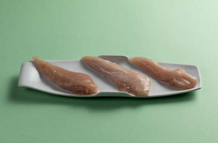 Raw chicken breasts on a green background. Elegant white plate.の写真素材
