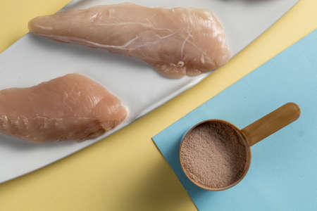 Raw chicken Breasts and a whey protein scoop cocoa flavor. Sport nutritionの写真素材