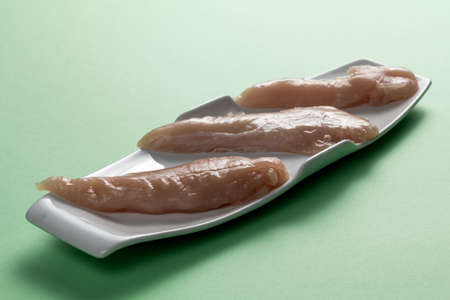 Raw chicken breasts on a green background. Modern white plate.の写真素材
