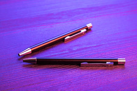 Two elegant pen on wood background and blue light. Business black pen.の写真素材