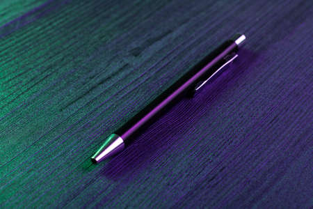 Elegant pen on wood background and green and blue light. Business black pen.の写真素材
