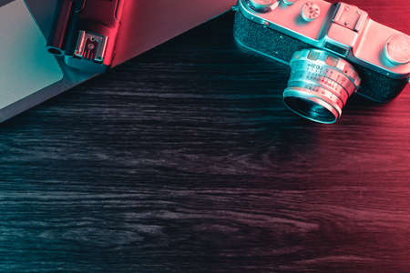 Old film camera and laptop on table. Blue and red light. Copy Spaceの写真素材