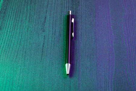 Elegant pen on wood background and green and blue light. Business black pen. Top viewの写真素材