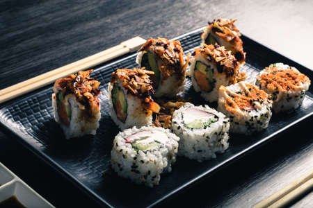 Sushi rolls with chopsticks on dark wood tableの写真素材