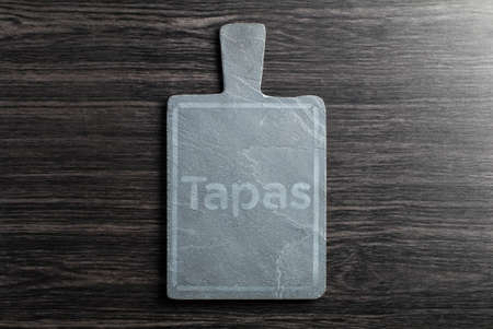Black slate board for serving with copy space, top view, on wood table background. Spanish Tapasの写真素材