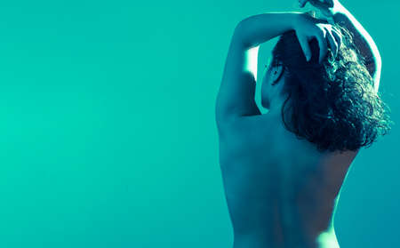 Naked girl on her back with her hands on her head. Emotional poses. Under water. Studio shot. Copy spaceの写真素材