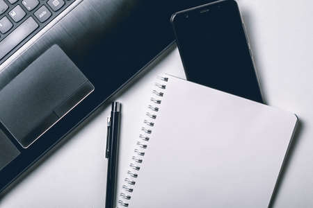 White office photography desk table with laptop, notebook, mobile phone and pen. Top view with copy space. Mock upの写真素材