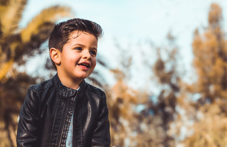 Fashion little boy wearing a leather jacket. Park or forest, outdoorの写真素材