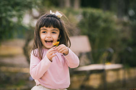 Little girl catching a flower in a park. Smiling and happy with a flower. Copy Spaceの写真素材