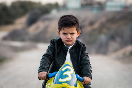 Angry little boy riding on motorcycle toyの写真素材