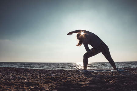 young woman doing yoga and stretching on the shoreの写真素材