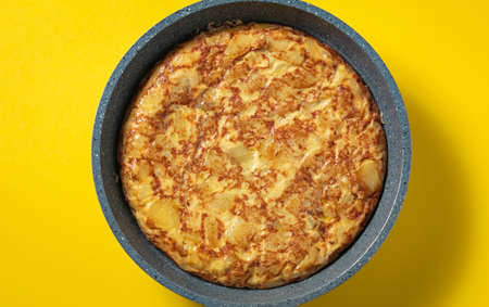 tortilla de patatas on skillet on yellow background, typical spanish dish.の写真素材
