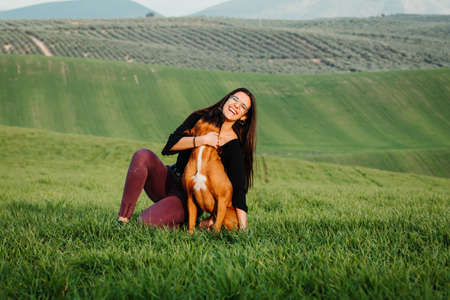 Beautiful woman playing with her dog. Outdoor portrait.の写真素材