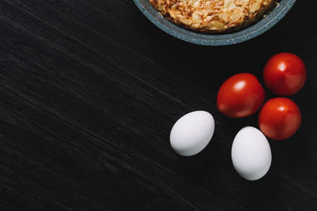 Spanish omelette on wood table, with eggs and tomatoesの写真素材