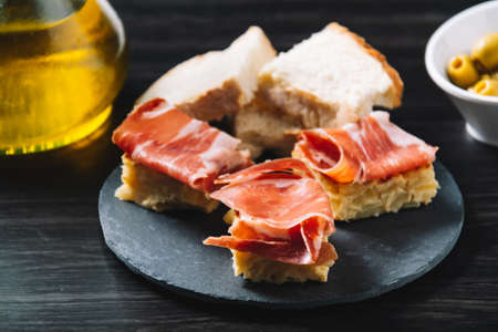 delicious Spanish potato omelette top with serrano ham, and olivesの写真素材